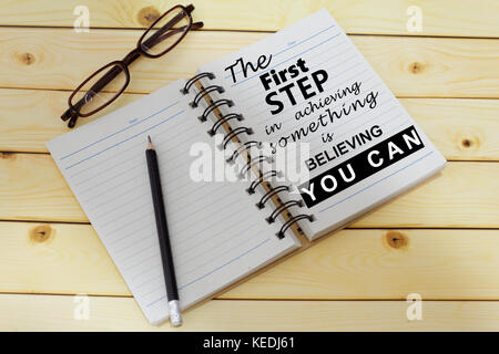 Satz der erste Schritt, etwas zu erreichen, ist zu glauben, die Sie auf eine Seite mit einem Notebook können geschrieben. Inspirierende und Motivierende. Stockfoto