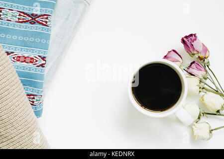 Tasse Kaffee und trocken rose Blumen und Vintage Kleidung auf weißem Hintergrund. top View Stockfoto