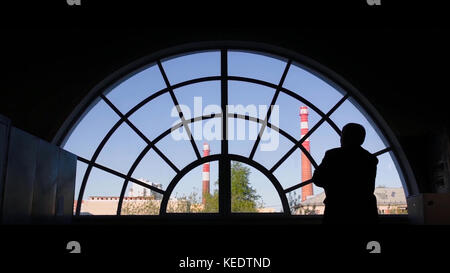 Alter Mann am Fenster. Rückansicht des alten Mannes, der zum runden Fenster kommt Stockfoto