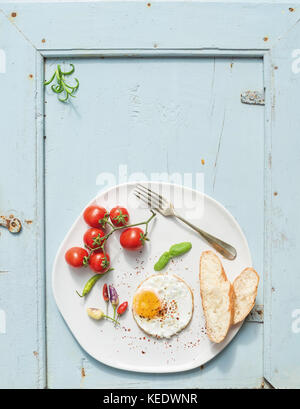 Frühstück eingestellt. Spiegelei, Scheiben Brot, Tomaten, Peperoni und Kräuter Stockfoto