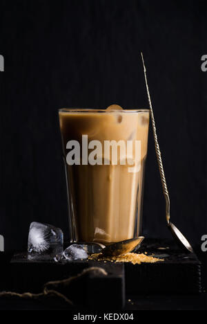 Eiskaffee mit Milch in ein hohes Glas, schwarzer Hintergrund Stockfoto