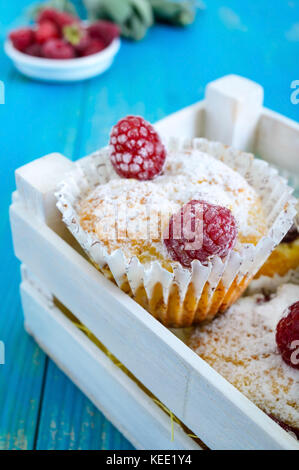 Quark Kuchen (Muffins) mit Himbeeren, dekoriert mit Puderzucker. in einem weißen Holzkasten dienen. frische Himbeeren in eine keramische Schüssel. Stockfoto