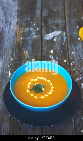 Kürbissuppe in blauer Schüssel, auf hölzernen Tisch Stockfoto