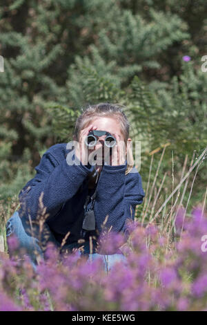 Junge Mädchen Birdwatching auf Lowland heath North Norfolk im Sommer (Model Released - Charlotte Tipling) Stockfoto