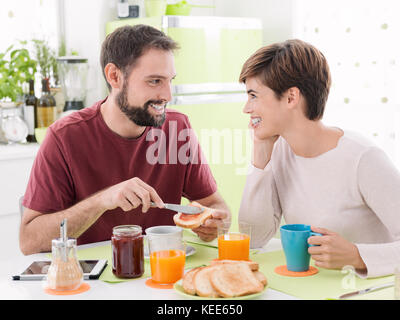Junge romantische Paar frühstücken zu Hause in der Küche, Sie sind zusammen essen und starrte auf die Augen, Romantik und Beziehungen co Stockfoto