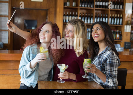 Gerne weibliche Freunde unter selfie mit Mobiltelefon, während sie Getränke in der Bar Stockfoto