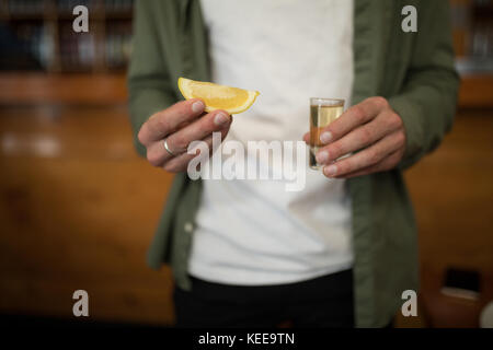 Den mittleren Abschnitt der Mann mit Tequila shot und Zitrone Keil in bar Stockfoto