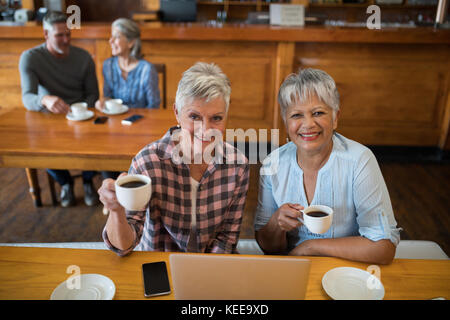 Portrait von lächelnden älteren Freunden in Tasse Tee im Restaurant Stockfoto