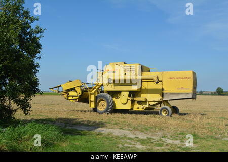 Alte offene Kabine gelb New Holland Mähdrescher Erntegut auf einem englischen Farm in 2017 Stockfoto