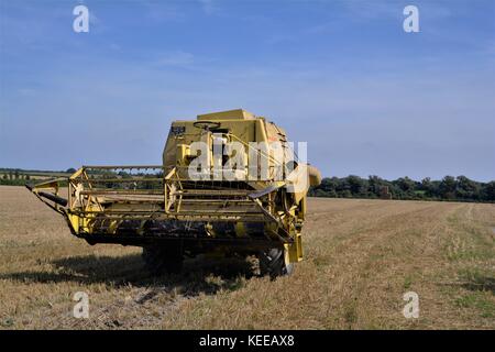 Alte offene Kabine gelb New Holland Mähdrescher Erntegut auf einem englischen Farm in 2017 Stockfoto