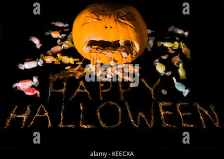 Einen geschnitzten Kürbis schaut zu erbrechen die Phrase happy halloween aus dem Fruchtfleisch umgeben von behandelt werden. Stockfoto