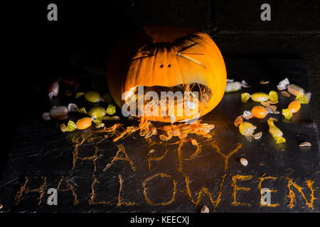 Einen geschnitzten Kürbis schaut zu erbrechen die Phrase happy halloween aus dem Fruchtfleisch umgeben von behandelt werden. Stockfoto