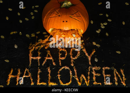 Einen geschnitzten Kürbis schaut zu erbrechen die Phrase happy halloween werden aus der Zellstoff Stockfoto