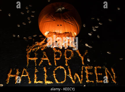 Einen geschnitzten Kürbis schaut zu erbrechen die Phrase happy halloween werden aus der Zellstoff Stockfoto