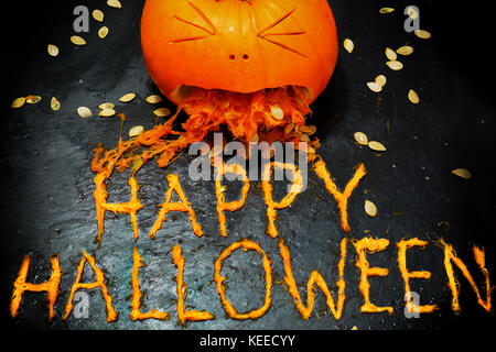 Einen geschnitzten Kürbis schaut zu erbrechen die Phrase happy halloween werden aus der Zellstoff Stockfoto