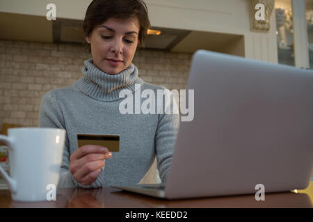 Frau tun Online Shopping mit einer Kreditkarte am Laptop zu Hause Stockfoto