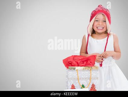 Digital composite von Mädchen gegen grauen Hintergrund mit Weihnachten Geschenk Tasche Stockfoto