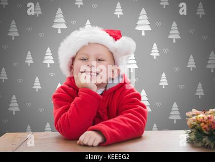 Digital composite der Junge gegen den grauen Hintergrund mit Weihnachten Santa Hut und Weihnachtsbaum Muster Stockfoto