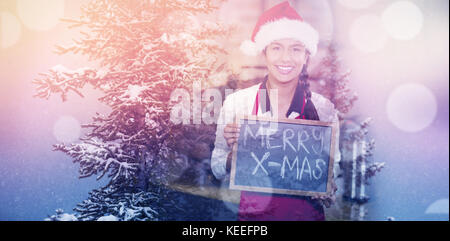 Verschneite Bäume im Winter gegen die hübsche Kellnerin mit Merry X-Mas Geschrieben am Schwarzen Brett Stockfoto