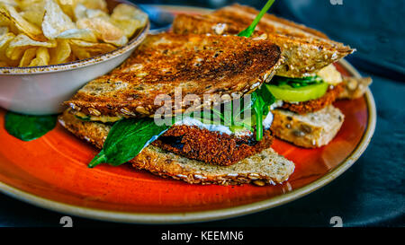 Ein Sandwich mit Panierte Auberginen, auf Toast, und serviert mit einer Seite von Kartoffelchips. Stockfoto