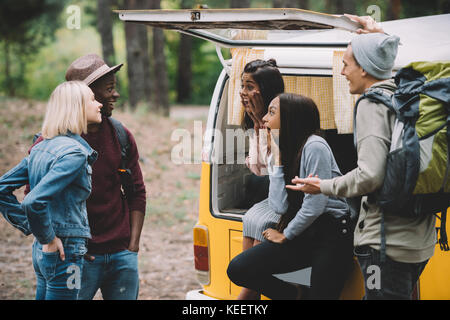 Junge schockiert multiethnischen Freunde Ausgabe Zeit zusammen im Wald mit retro Minivan Stockfoto