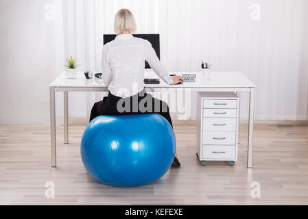 Geschäftsfrau, Sitzen auf Fitness Ball Arbeiten im Büro Stockfoto