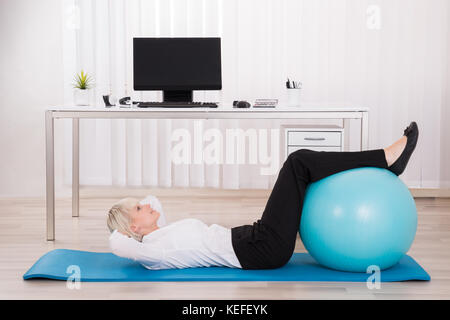 Junge Geschäftsfrau Trainieren mit Fitness Ball im Büro Stockfoto