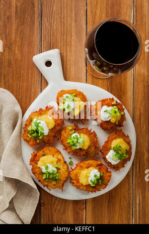 Kartoffelpuffer, latkes oder Boxty und Saucen aus Sauerrahm, Joghurt, Apfelmus und fein gehackten Frühlingszwiebeln auf einem hölzernen Tisch der Platten Stockfoto