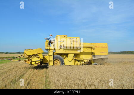 Vintage New Holland open cabyellow Mähdrescher in Aktion auf der Farm, Stockfoto