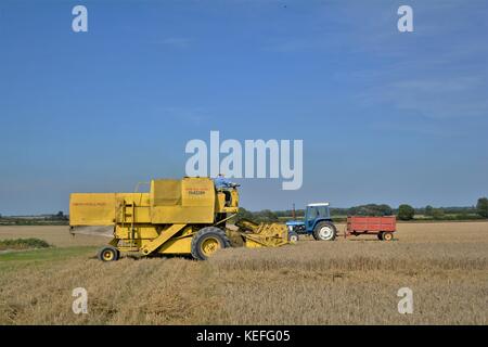 Vintage New Holland open cabyellow Mähdrescher in Aktion auf der Farm, Stockfoto