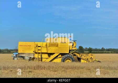 Vintage New Holland open cabyellow Mähdrescher in Aktion auf der Farm, Stockfoto