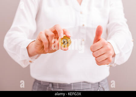 Geschäftsfrau Die bitcoin Gold Münze und Daumen hoch halten, der Erhöhung zu genießen. Stockfoto