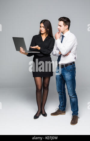 Der junge Unternehmer und Geschäftsfrau mit Notebooks kommunizieren auf grauem Hintergrund Stockfoto