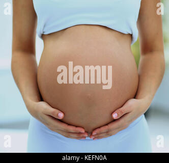 Frau hält ihren Babybauch Stockfoto