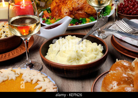 Eine Schüssel mit Kartoffelpüree auf einen Tisch unter den Pumpkin Pie, gebackene Türkei, Cranberry-orange Sauce, ein Glas Weißwein für Thanksgiving Stockfoto