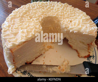 Ein halbes gegessen cremefarbener Kuchen auf eine Platte mit einem Messer auf sie. Stockfoto
