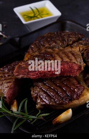 Gegrilltes Rindersteak mit Gewürzen auf dunklem Hintergrund Stockfoto