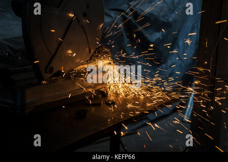 Arbeiter schneiden Eisenplatte mit Mahlwerk in alten Metallwerkstatt Stockfoto
