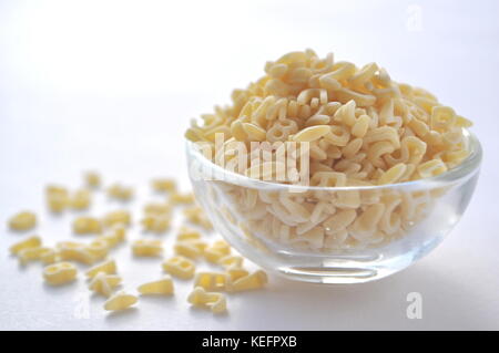 Alphabet Nudeln für Kindergerichte. ABC Pasta. Trockene Teigwaren in eine Glasschüssel isoliert auf Weiss, aus der Nähe. Stockfoto