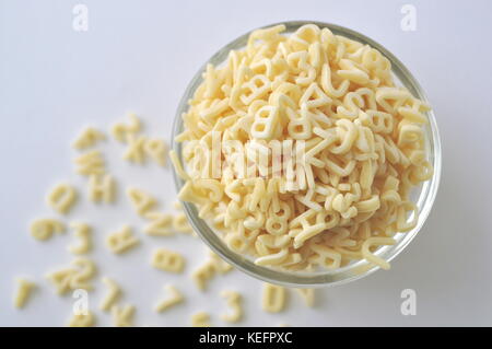 Alphabet Nudeln für Kindergerichte. ABC Pasta. Trockene Teigwaren in eine Glasschüssel isoliert auf Weiss, aus der Nähe. Stockfoto