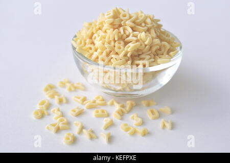 Alphabet Nudeln für Kindergerichte. ABC Pasta. Trockene Teigwaren in eine Glasschüssel isoliert auf Weiss, aus der Nähe. Stockfoto