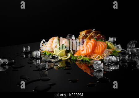 Eine Vielzahl von Sushi mit Stücken von schmelzendem Eis auf einem schwarzen Hintergrund mit Reflektion Stockfoto