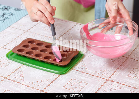 Rosa Schokolade geschmolzen und Herzen Form in der Küche Stockfoto