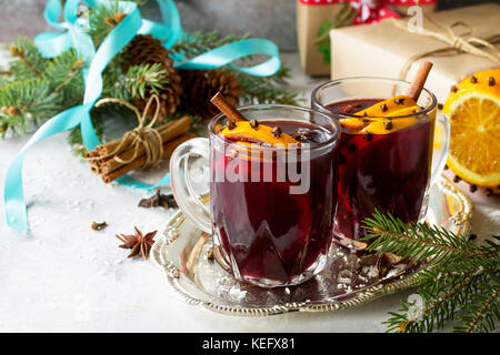 Hausgemachte Weihnachten cocktail Glühwein Rotwein mit Zimtstangen, Orangen und Nelken, in zwei Tassen serviert auf einem grauen Stein oder Schiefer. kopieren. Stockfoto