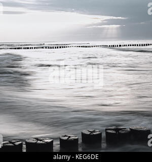 Monochromes Bild der Ostsee mit wellenbrechern bei Sonnenuntergang Stockfoto