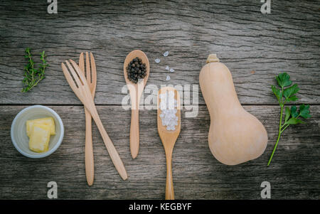 Gesunde Ernährung Konzept. Zutaten für Kürbissuppe mit rustikalen Holzmöbeln Hintergrund. frische Kürbis mit Kräuter, Zitrone, Thymian, Petersilie und Pfeffer. Stockfoto