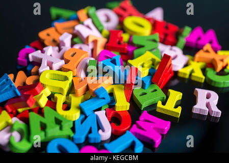 Viele bunte Buchstaben auf schwarzem Hintergrund aus Kunststoff. Stockfoto