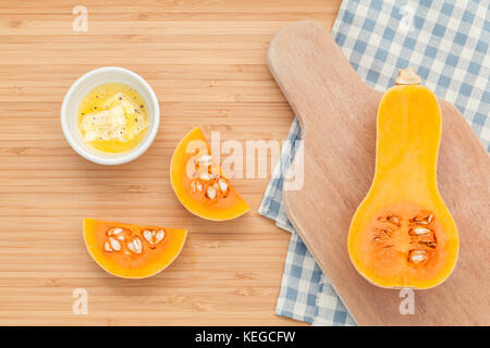 Gesunde Ernährung Konzept. frische Kürbis Kürbis in Scheiben schneiden und mit Butter in die Schüssel für Kürbissuppe auf Bambus Schneidebrett. Stockfoto