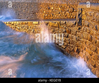 Kanalinseln. Guernsey. Saint Peter Port. Wellen brechen an der Hafenmauer und dem Slipway. Stockfoto