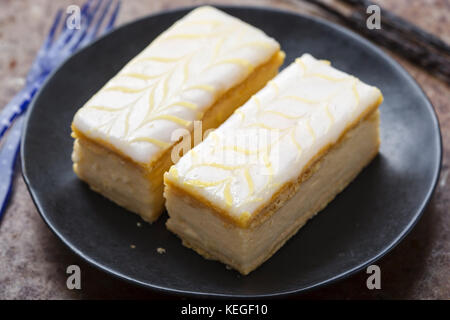 Vanille Schichten. Blätterteig gefüllt mit Vanillepudding gekrönt mit Fondant Zuckerglasur. Stockfoto